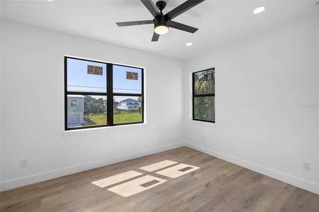 a view of empty room with wooden floor and fan