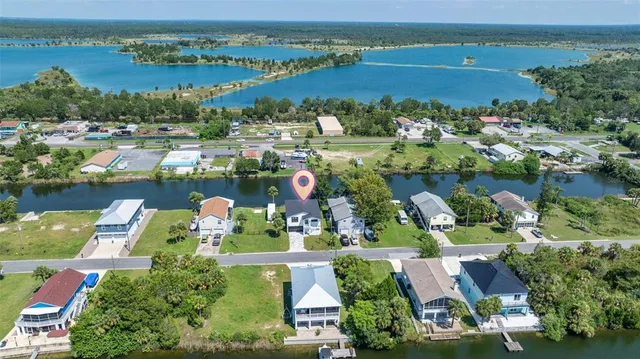 an aerial view of lake and residential houses with outdoor space and swimming pool