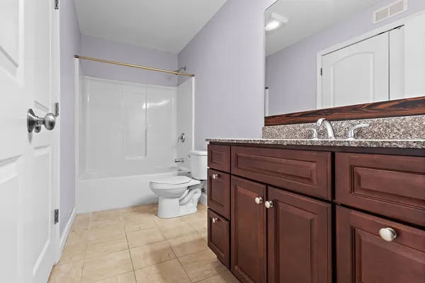 a bathroom with a granite countertop toilet a sink and a bathtub