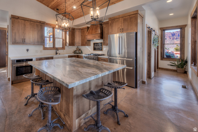4173 Shadowfax Run, Unit 5 Moab, UT 84532 - Photo 18 of 41 Kitchen with stainless steel appliances, concrete flooring, Knotty Alder cabinetry, Leathered Quartzite island, and a breakfast bar