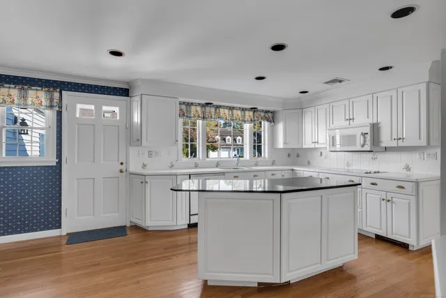 a kitchen with granite countertop white cabinets and wooden floor