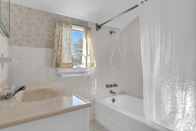 a bathroom with a tub a sink and a window