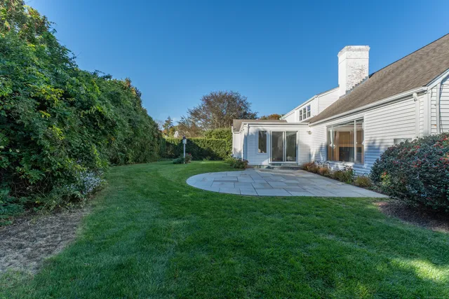 a view of a house with a big yard potted plants and large tree