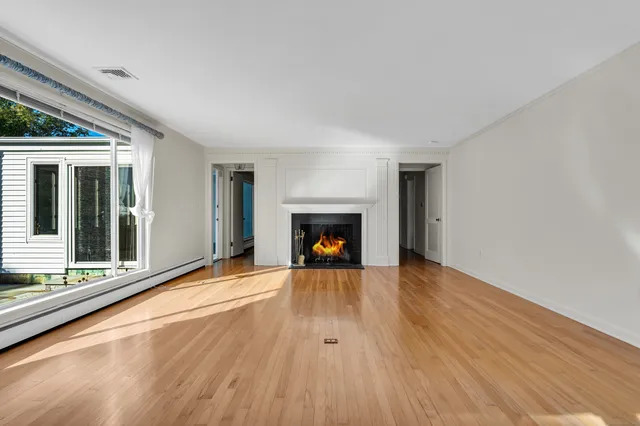 a view of a room with wooden floor a fireplace and window