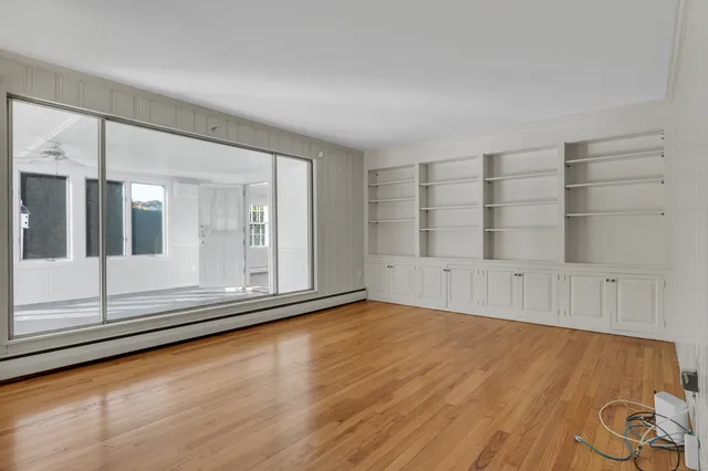 a view of an empty room with wooden floor and windows