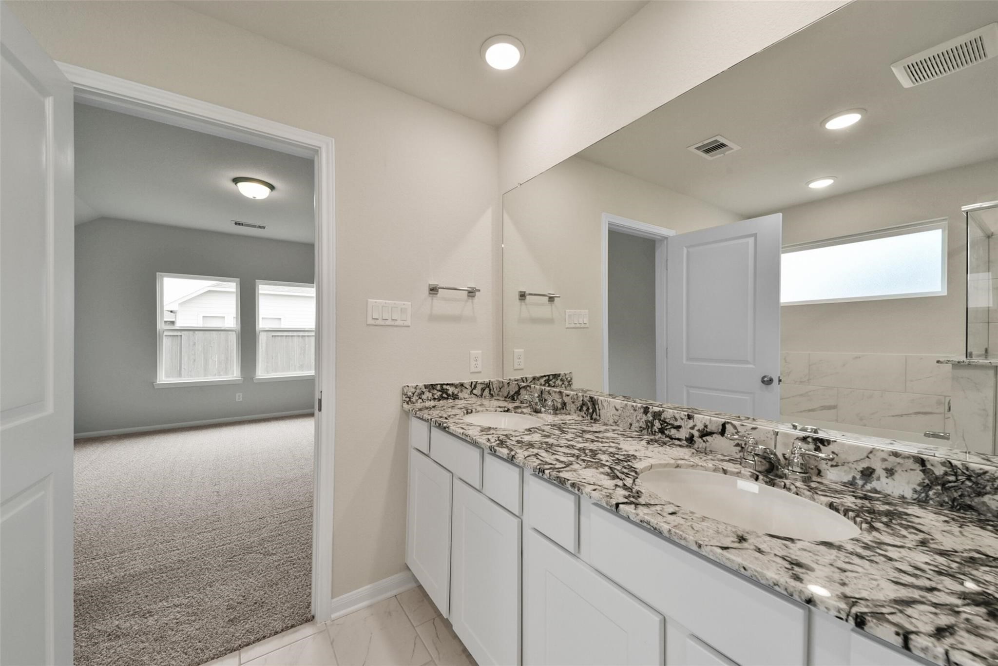 10522 Plumas Run Drive Rosharon, TX 77583 - Photo 19 of 29 Modern en-suite featuring a dual granite vanity, ample storage, and a bright tiled shower with a privacy window.