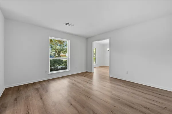 a view of an empty room with wooden floor and a window