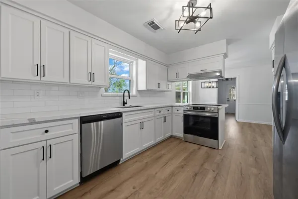 a kitchen with cabinets wooden floor and stainless steel appliances