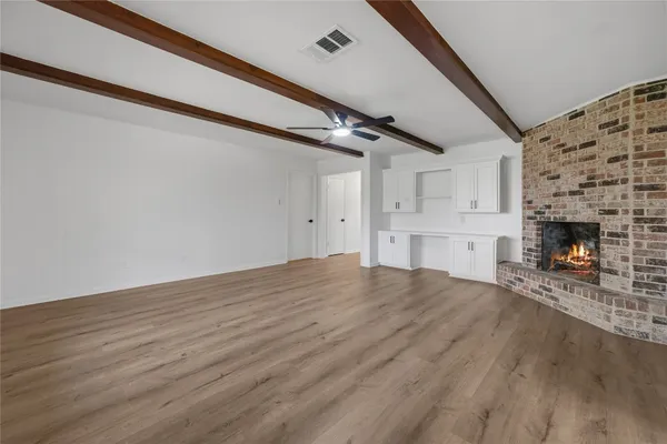 a view of empty room with wooden floor and fireplace
