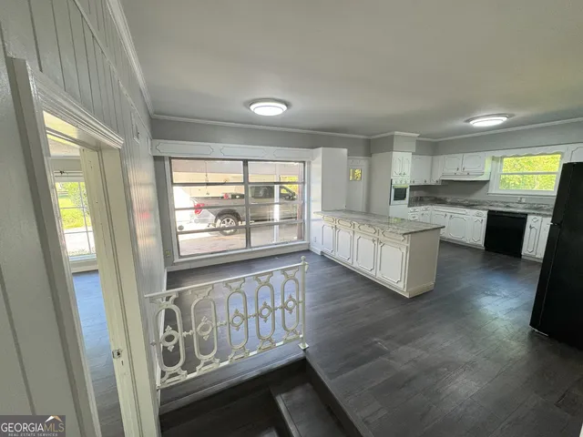a kitchen with white cabinets and wooden floor