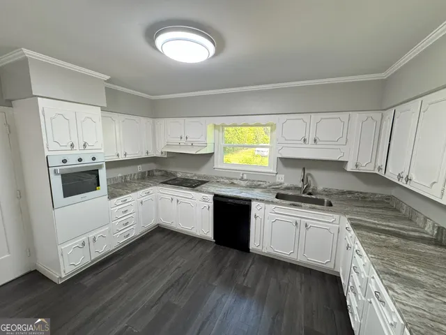 a white kitchen with sink and cabinets
