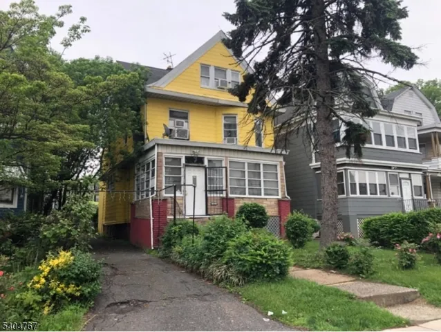 a front view of a house with a yard and trees