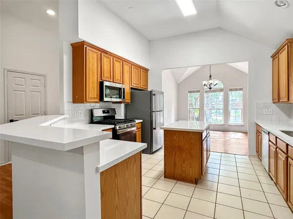 a kitchen with stainless steel appliances granite countertop a refrigerator a sink a stove with white cabinets