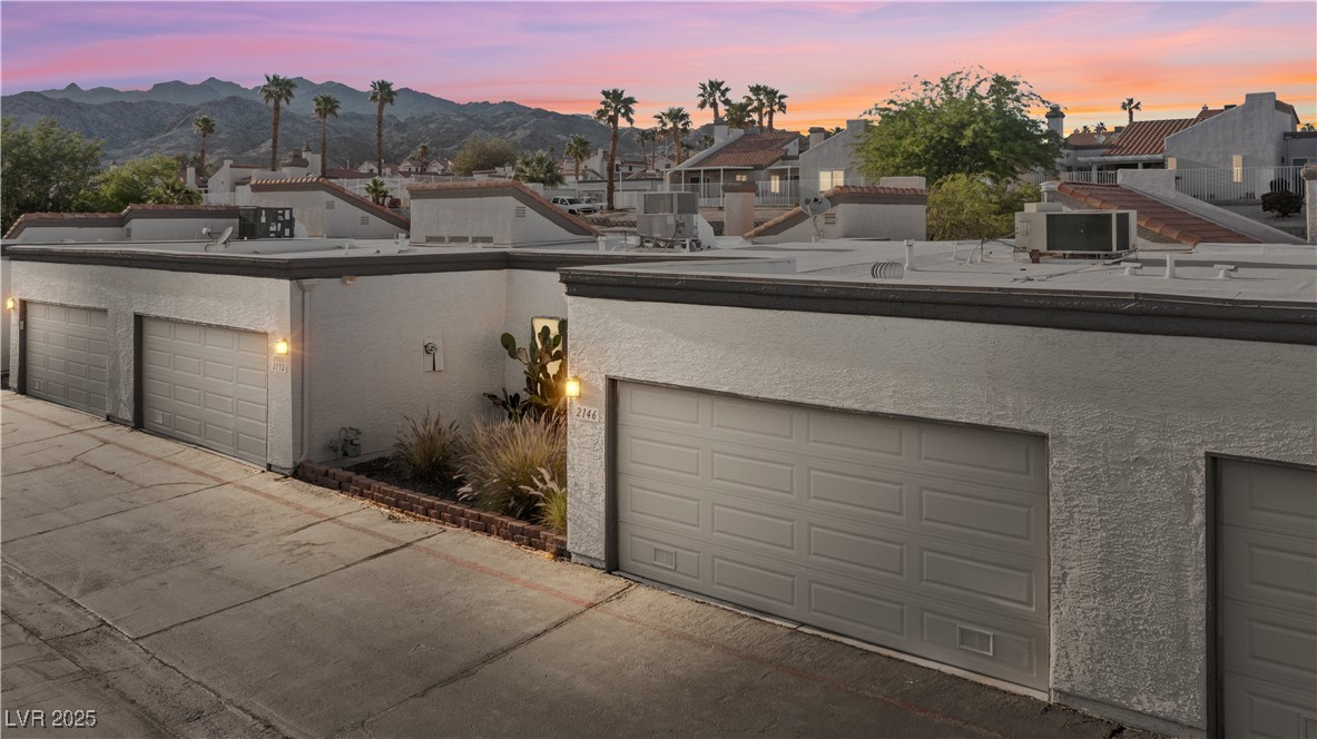Front of home at dusk with 2 car garage, featuring stucco siding.