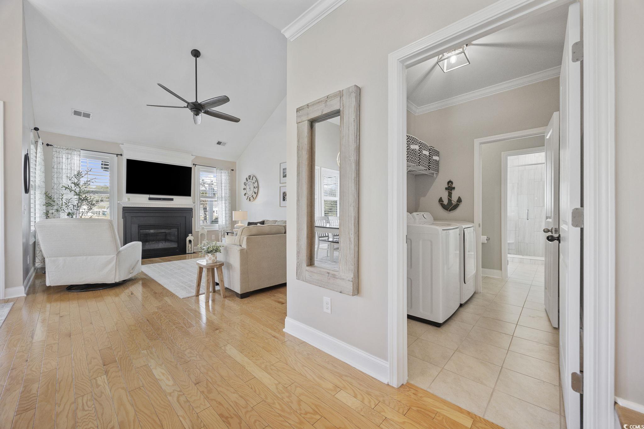 147 Hyacinth Loop Murrells Inlet, SC 29576 - Photo 11 of 40 Living room with a glass covered fireplace, lofted ceiling, light wood-type flooring, ornamental molding, and ceiling fan