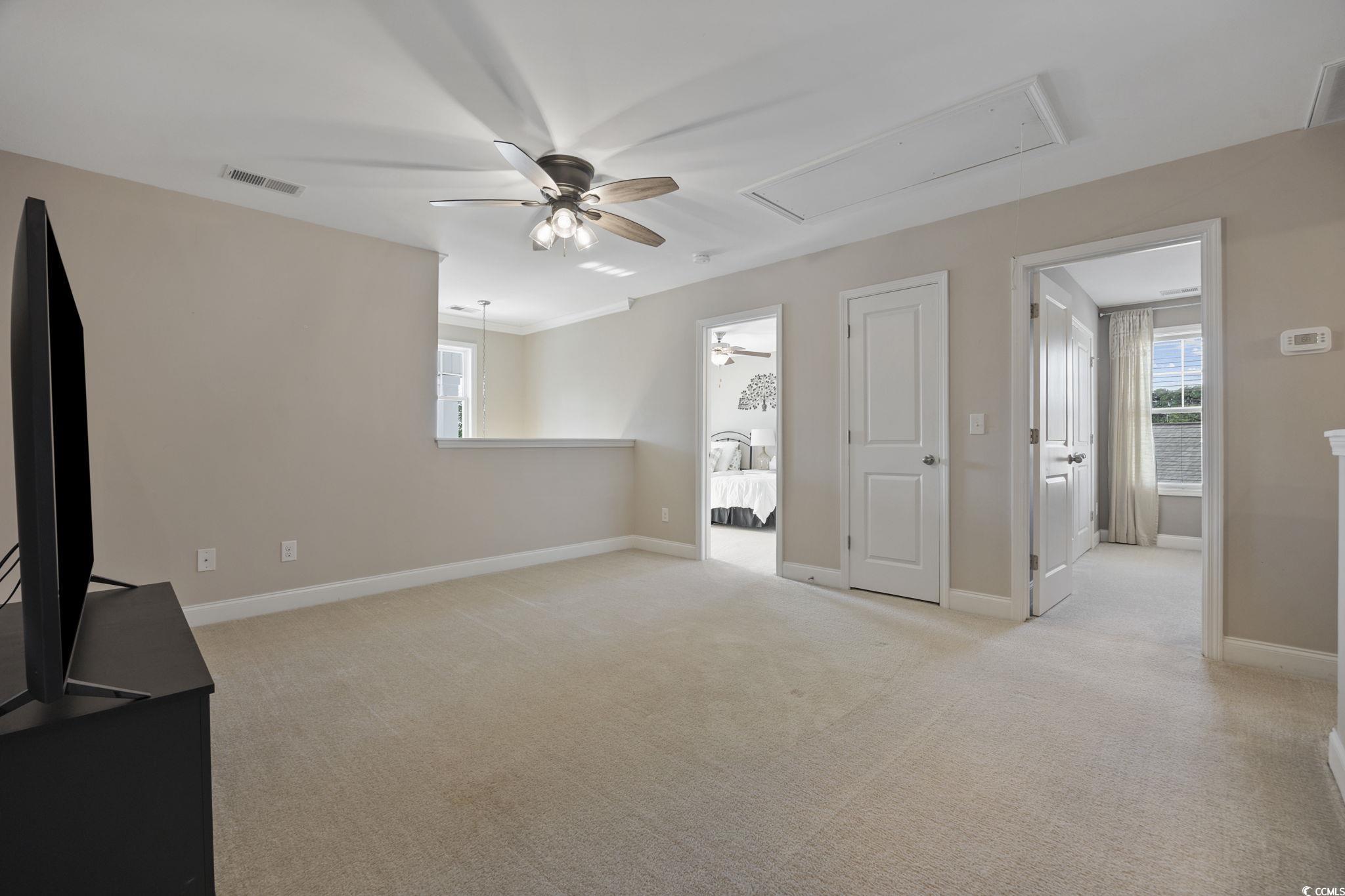 147 Hyacinth Loop Murrells Inlet, SC 29576 - Photo 18 of 40 Unfurnished living room featuring a ceiling fan, light carpet, and attic access