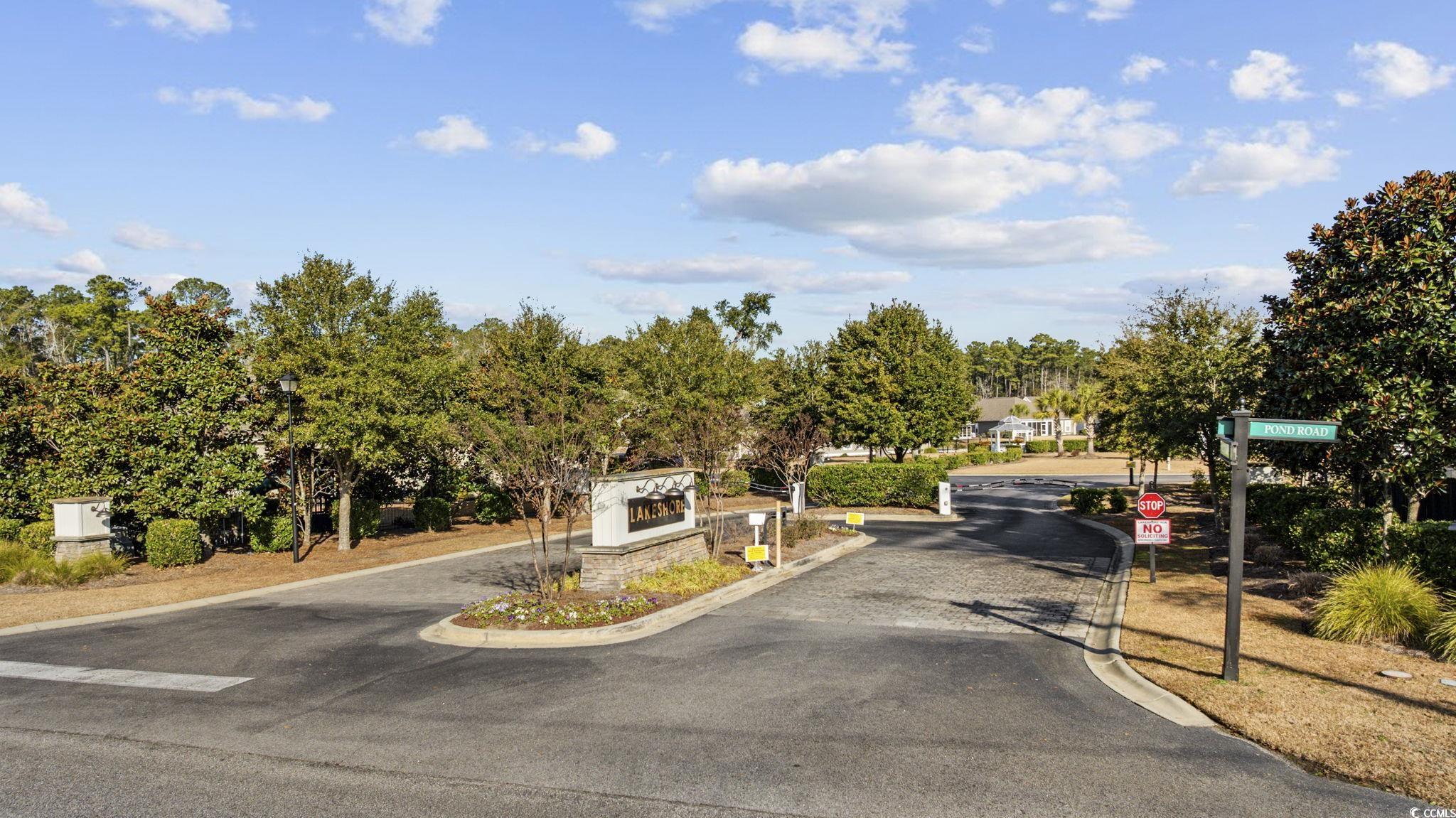 147 Hyacinth Loop Murrells Inlet, SC 29576 - Photo 38 of 40 View of asphalt road with traffic signs, curbs, and a gated entry