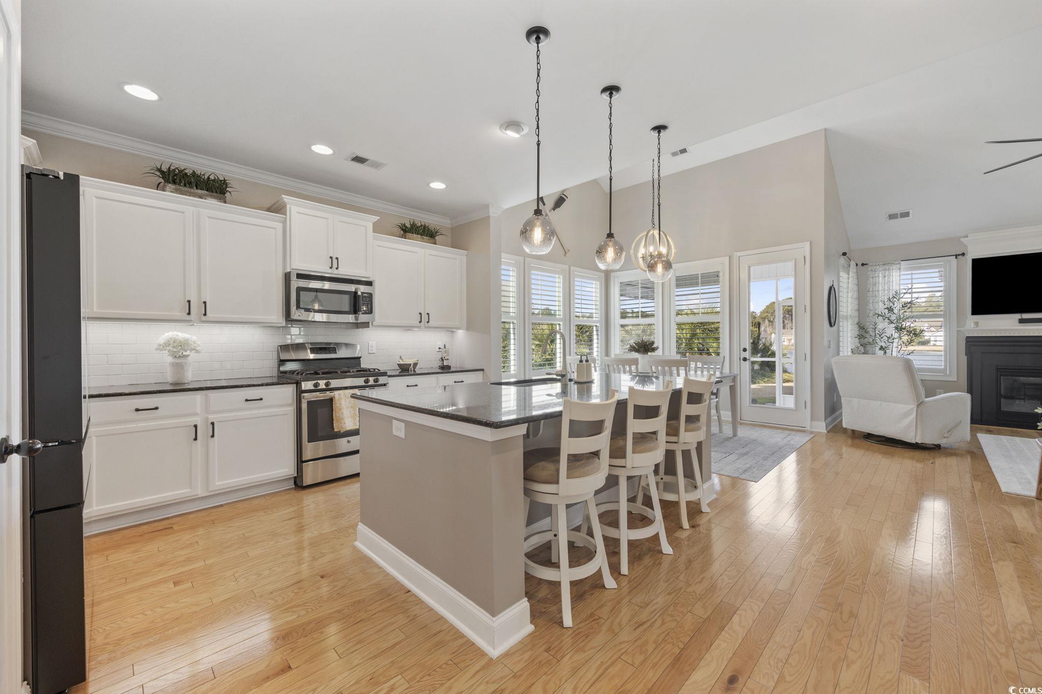 147 Hyacinth Loop Murrells Inlet, SC 29576 - Photo 39 of 40 Kitchen with a breakfast bar, appliances with stainless steel finishes, open floor plan, an island with sink, and a glass covered fireplace