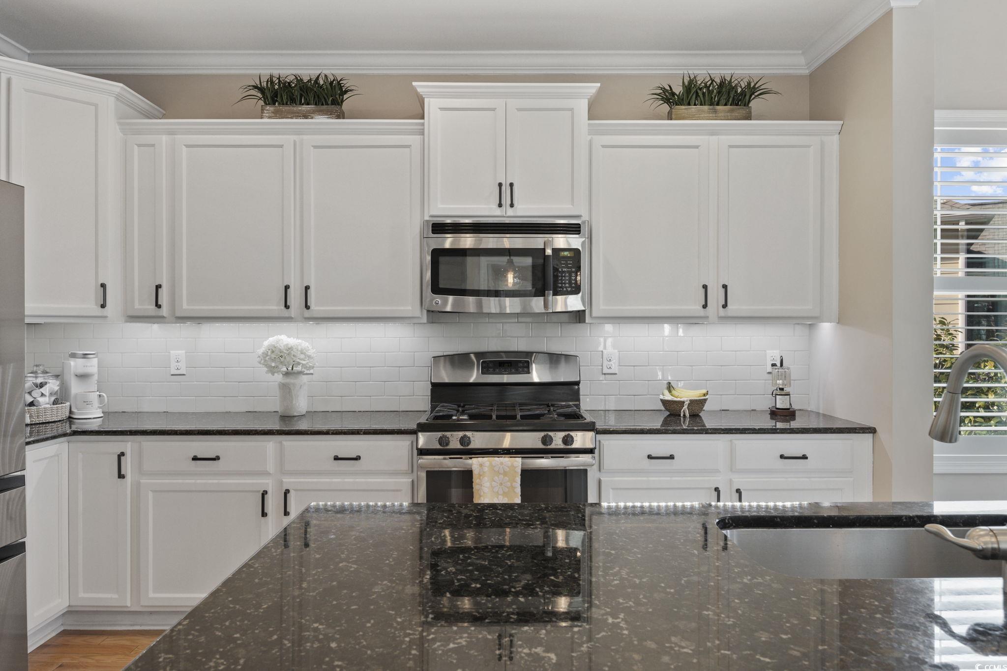 147 Hyacinth Loop Murrells Inlet, SC 29576 - Photo 5 of 40 Kitchen with dark stone counters, stainless steel appliances, crown molding, white cabinets, and plenty of natural light