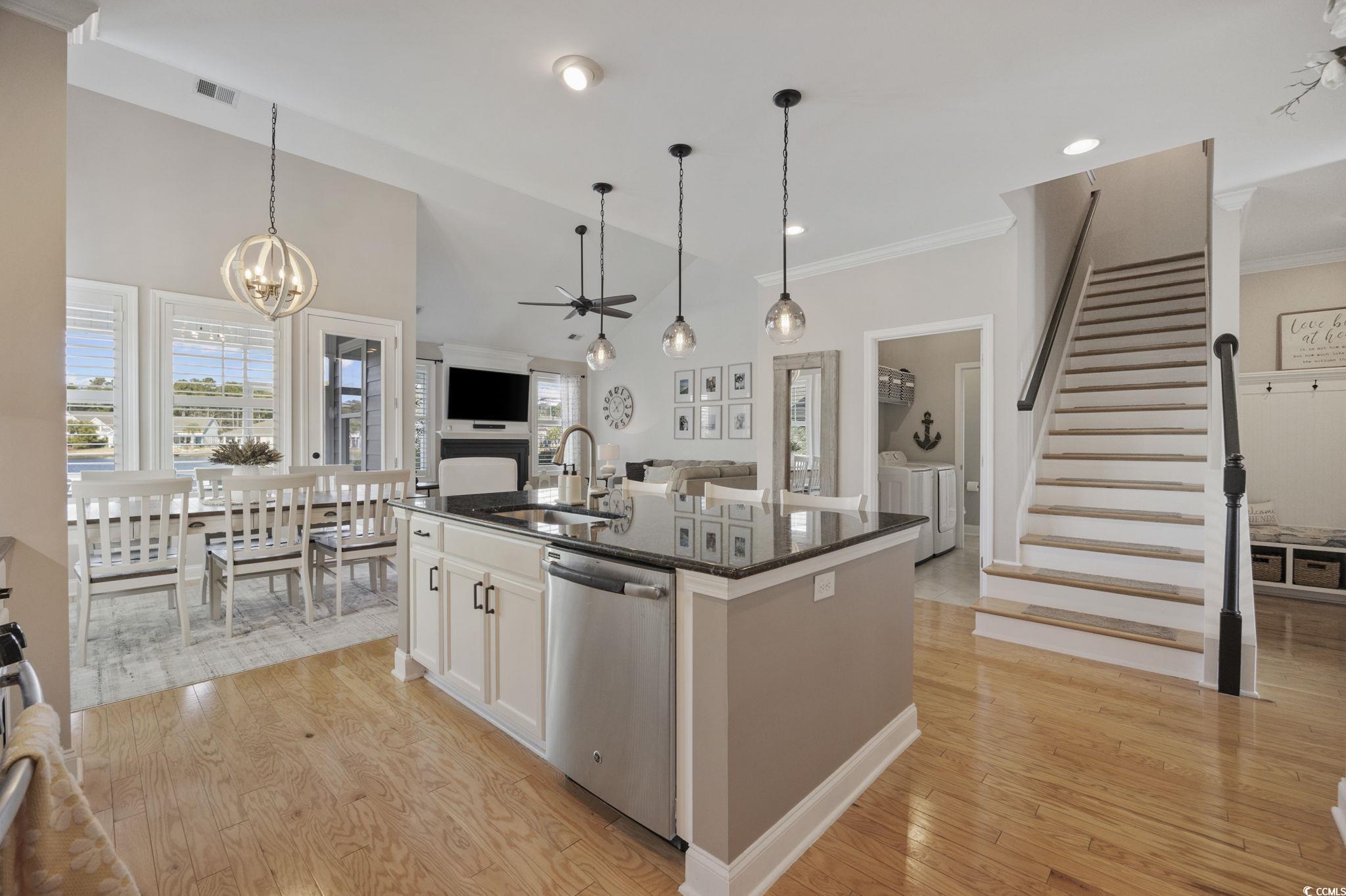 147 Hyacinth Loop Murrells Inlet, SC 29576 - Photo 40 of 40 Kitchen featuring open floor plan, decorative light fixtures, stainless steel dishwasher, light wood-style flooring, and crown molding