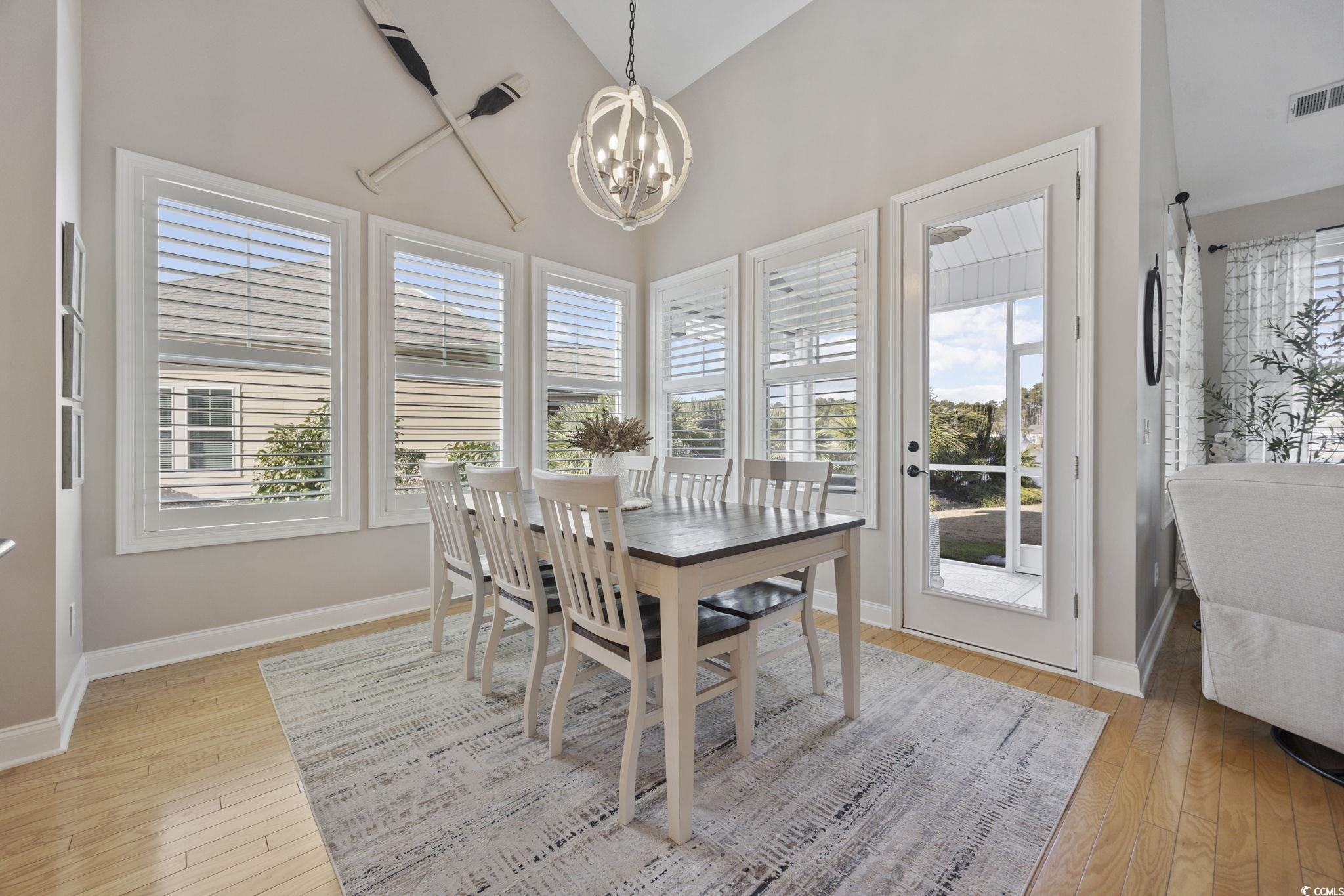 147 Hyacinth Loop Murrells Inlet, SC 29576 - Photo 6 of 40 Dining space with high vaulted ceiling, light wood-style flooring, and a chandelier