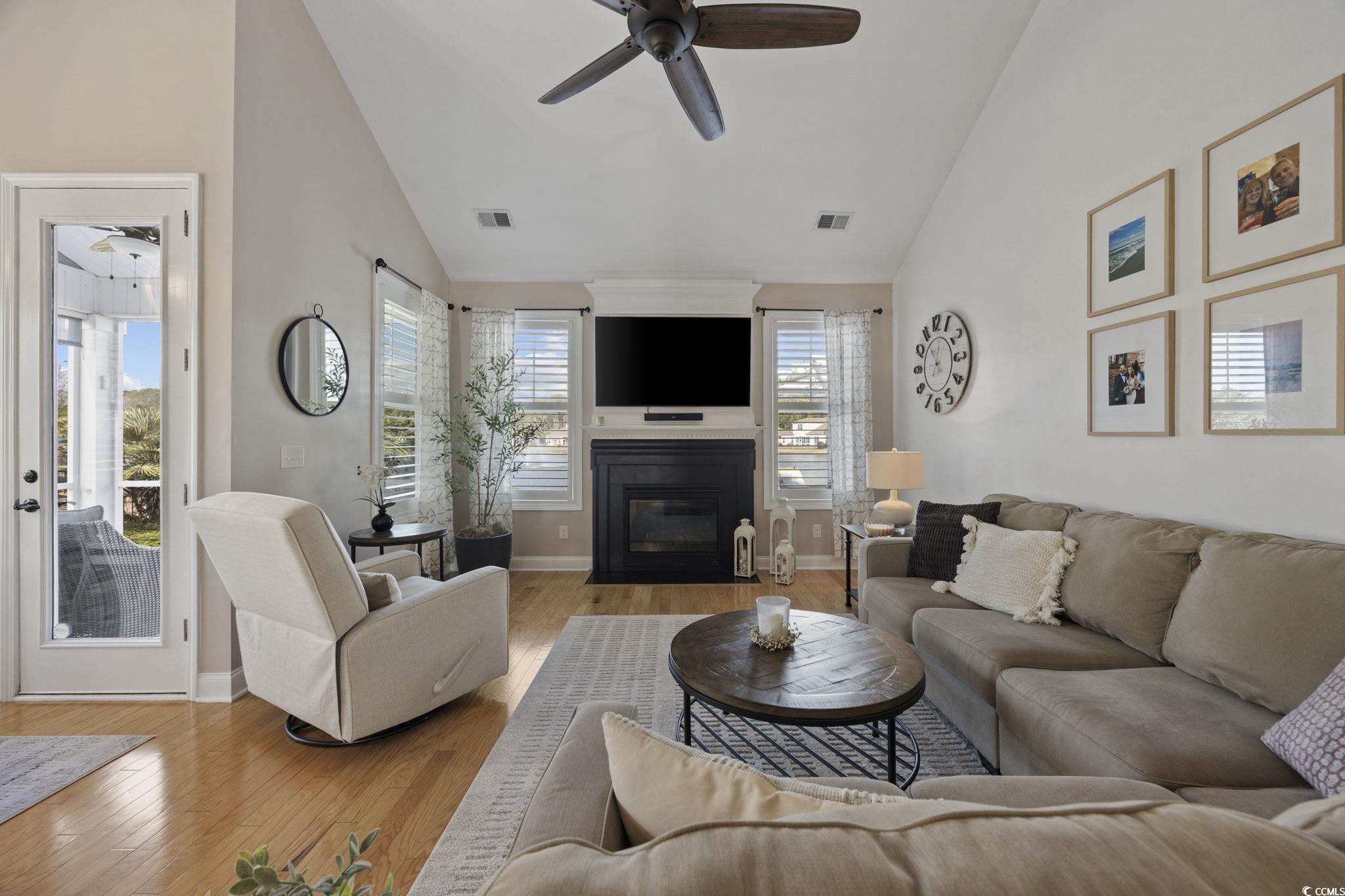 147 Hyacinth Loop Murrells Inlet, SC 29576 - Photo 7 of 40 Living room featuring lofted ceiling, a ceiling fan, light wood-type flooring, and a large fireplace