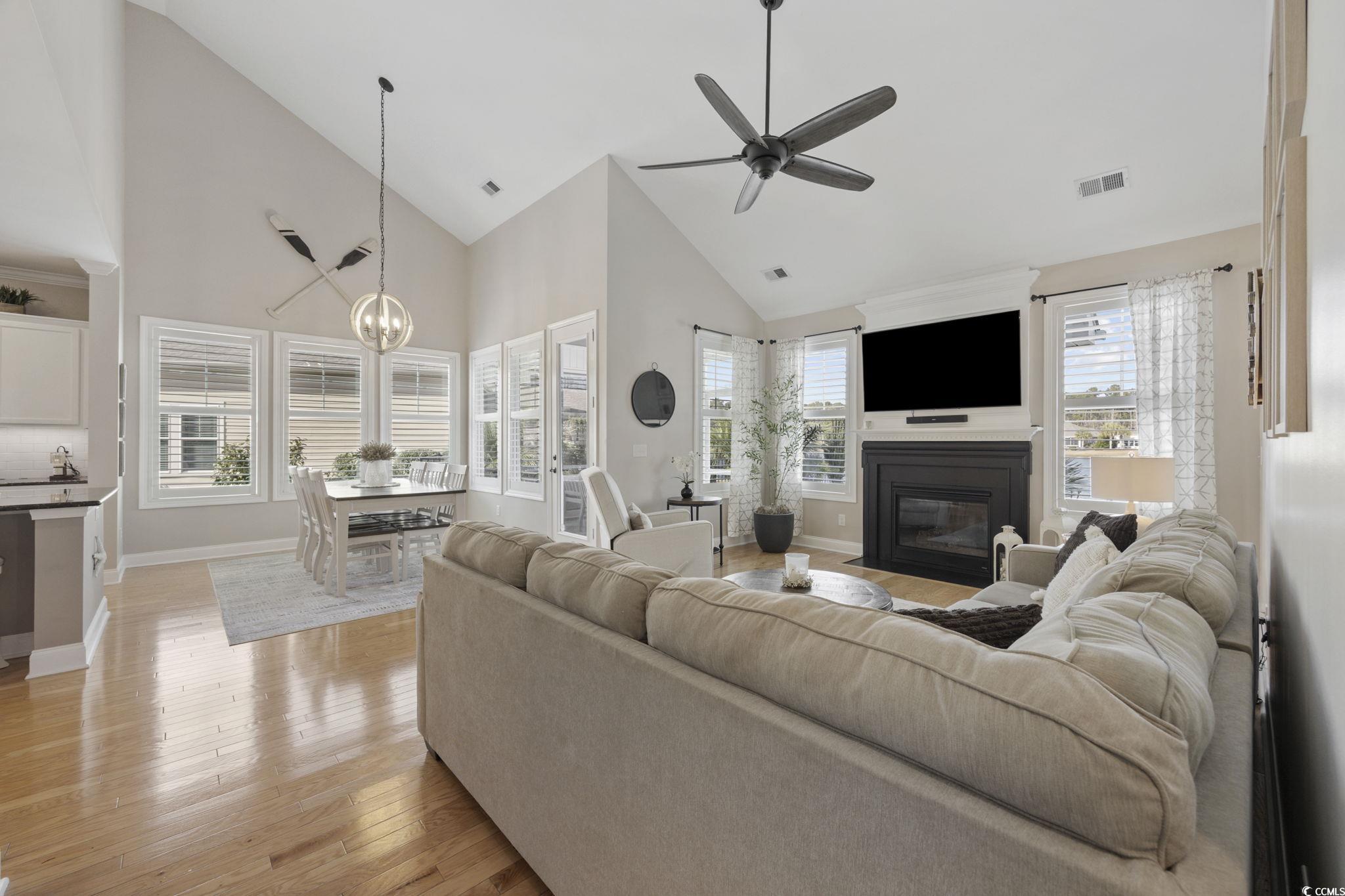 147 Hyacinth Loop Murrells Inlet, SC 29576 - Photo 8 of 40 Living area featuring high vaulted ceiling, a fireplace with flush hearth, a chandelier, light wood finished floors, and ceiling fan