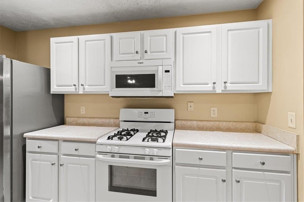 329 Meadows Lane Canton, GA 30114 - Photo 10 of 36 a kitchen with granite countertop white cabinets and white appliances