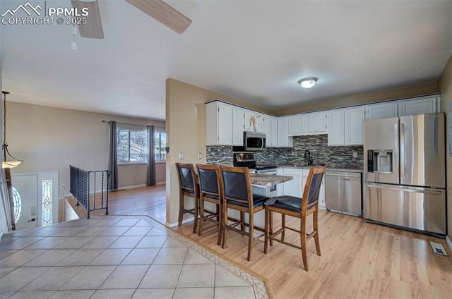 Kitchen featuring white cabinetry, light tile patterned floors, backsplash, visible vents, and appliances with stainless steel finishes