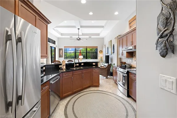 a kitchen with stainless steel appliances granite countertop a refrigerator a stove and a sink with wooden floor