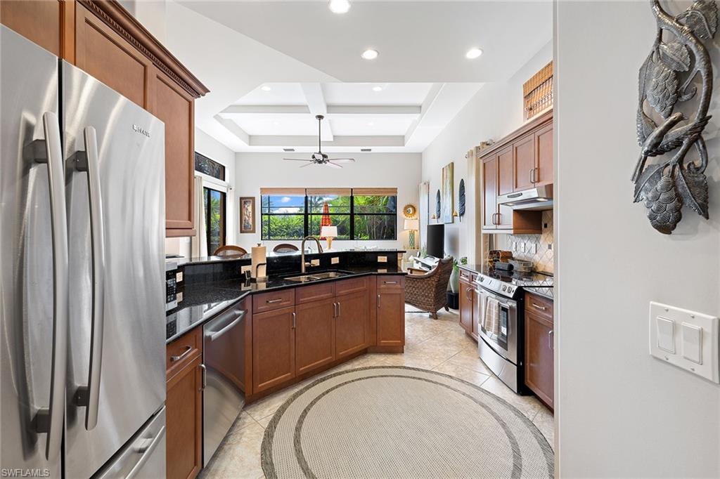 6513 Caldecott Drive Naples, FL 34113 - Photo 14 of 33 a kitchen with stainless steel appliances granite countertop a refrigerator a stove and a sink with wooden floor