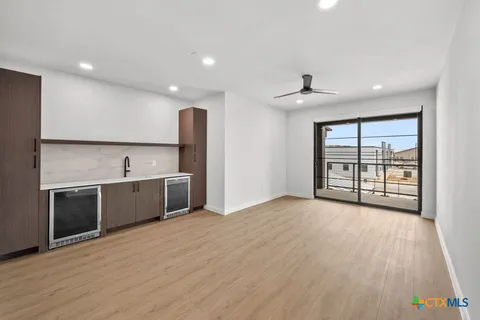 a large living room with stainless steel appliances granite countertop a couch a flat screen tv and a large window with wooden floor