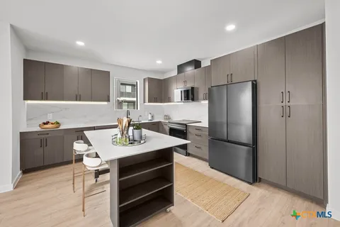 a kitchen with stainless steel appliances a refrigerator sink and wooden floor