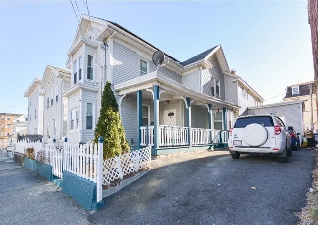 a white house with a small yard and wooden fence