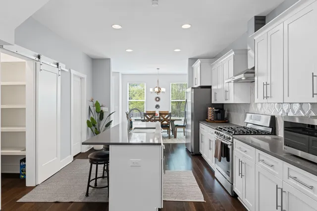 a kitchen with stainless steel appliances a stove a sink cabinets and a wooden floor