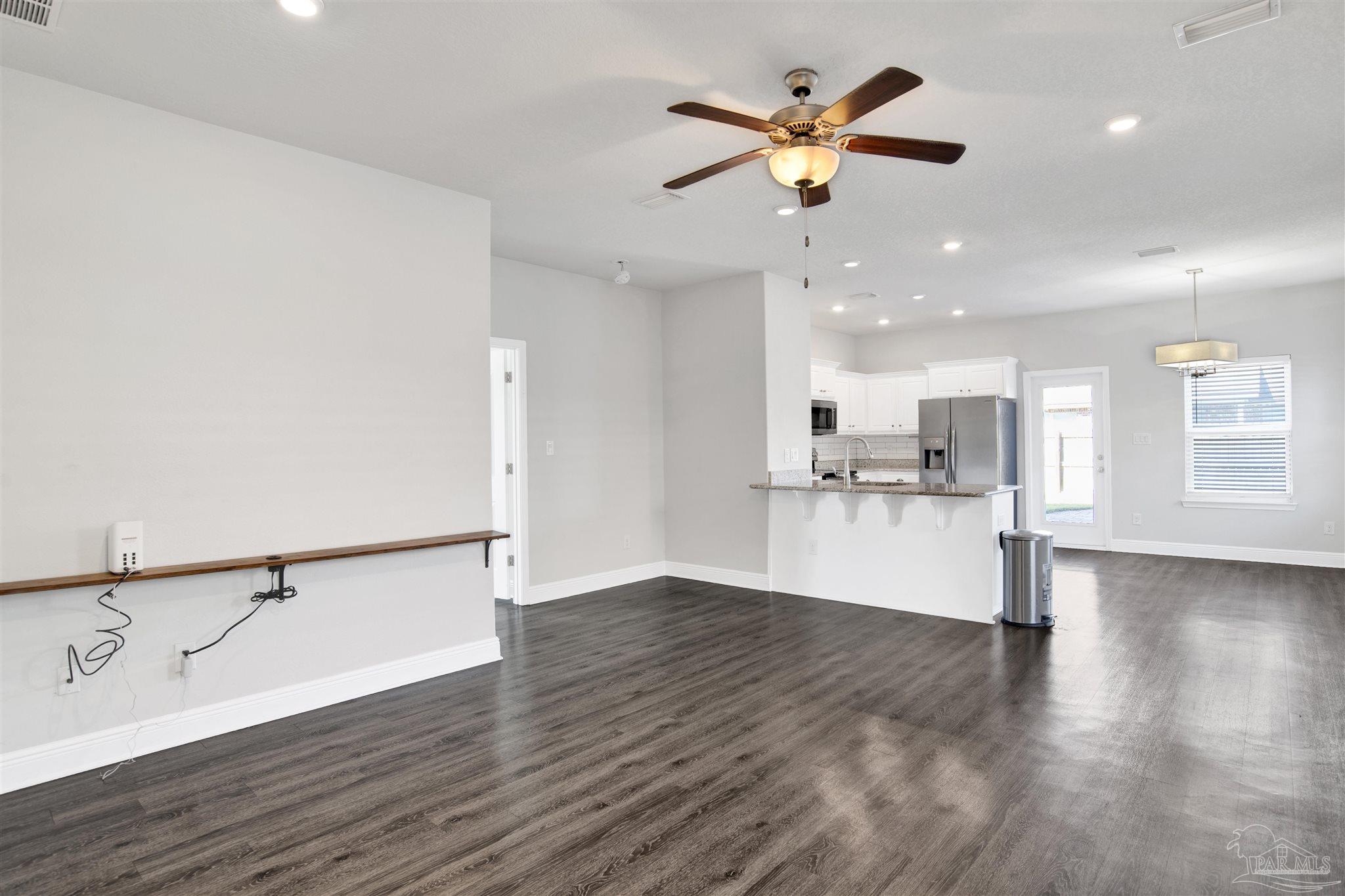 12295 Pinfish Road Pensacola, FL 32506 - Photo 7 of 34 a view of an empty room with wooden floor and a ceiling fan