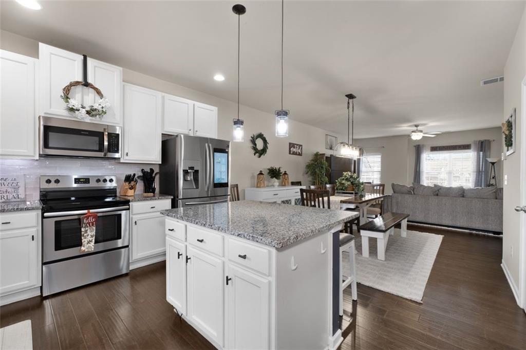 4180 Chatham Ridge Drive Buford, GA 30518 - Photo 12 of 43 a kitchen with stainless steel appliances granite countertop a stove a sink refrigerator and a wooden floor