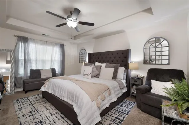 a spacious bedroom with a bed a couch and a large window