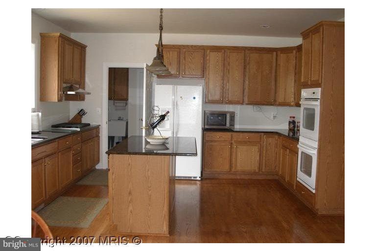 7201 Wesley Road Springfield, VA 22150 - Photo 6 of 11 a kitchen with a sink a stove cabinets and a wooden floor