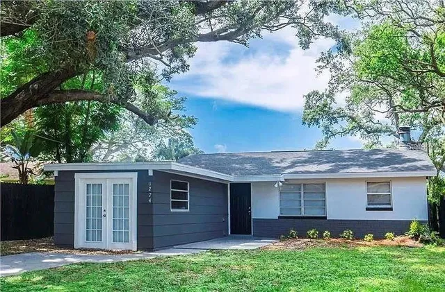 a view of a house with a yard and a large tree