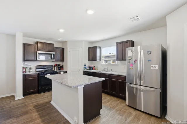 a kitchen with stainless steel appliances granite countertop a refrigerator stove microwave and sink