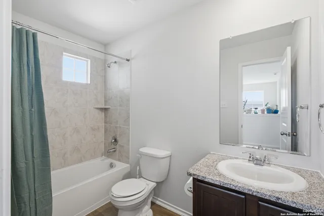 a bathroom with a granite countertop sink a toilet and shower