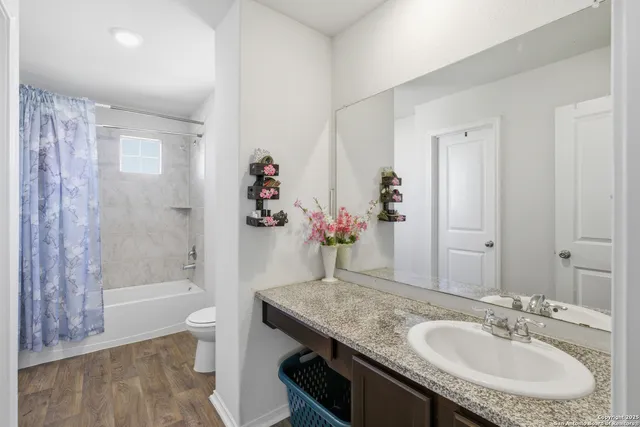 a bathroom with a granite countertop sink a toilet and shower