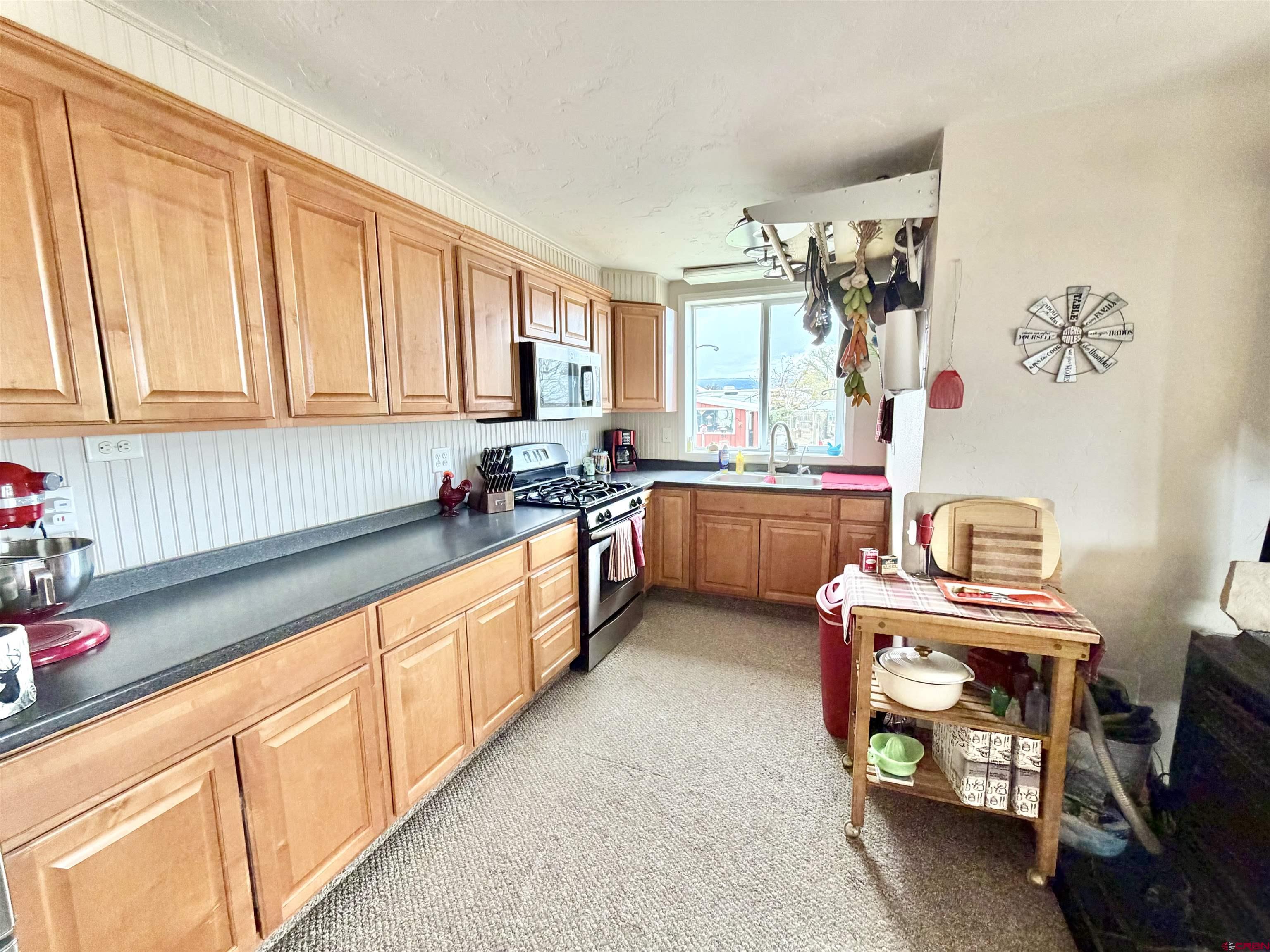 3998 5500th Road Olathe, CO 81425 - Photo 32 of 45 a kitchen with granite countertop a sink dishwasher stove and cabinets