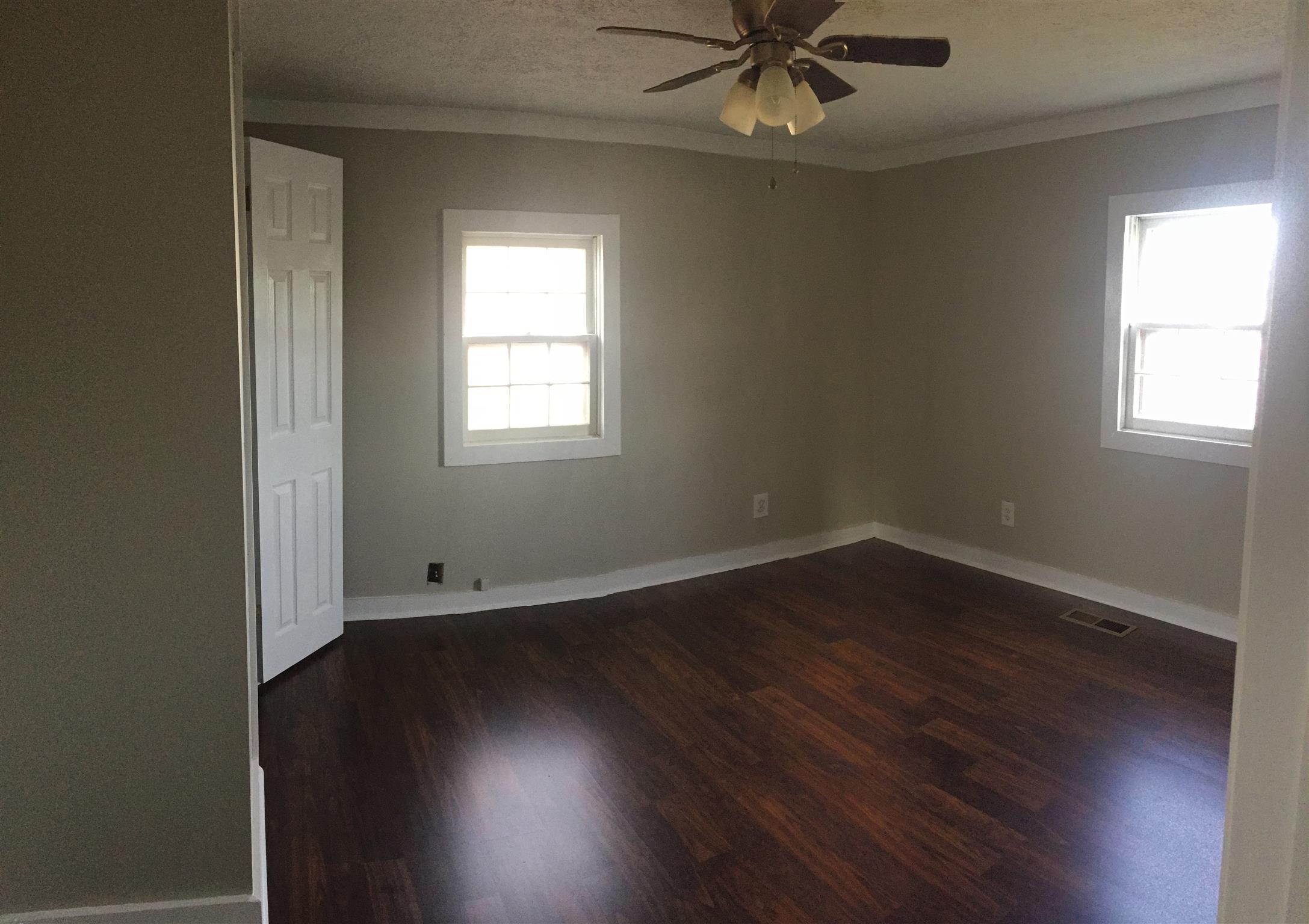 506 Dorris Road Portland, TN 37148 - Photo 5 of 8 an empty room with wooden floor a ceiling fan and windows