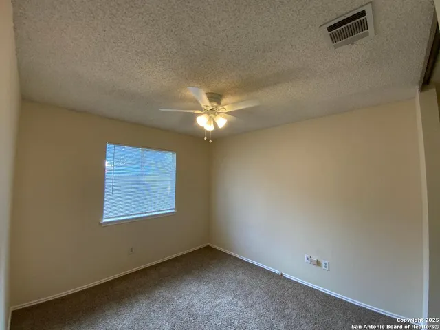 an empty room with a window and a fan