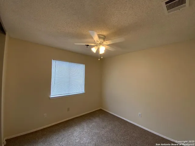 an empty room with a window and a ceiling fan