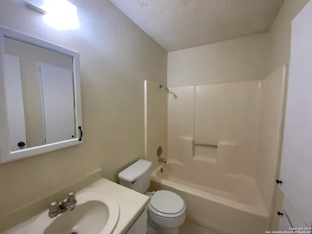 a bathroom with a bathtub shower sink mirror vanity and toilet