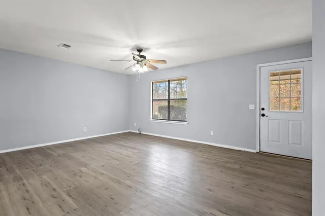 a view of an empty room with a window and wooden floor