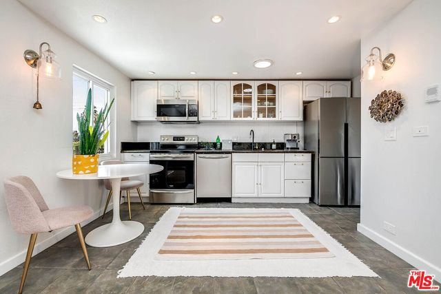 a kitchen with stainless steel appliances granite countertop a refrigerator a stove and a sink